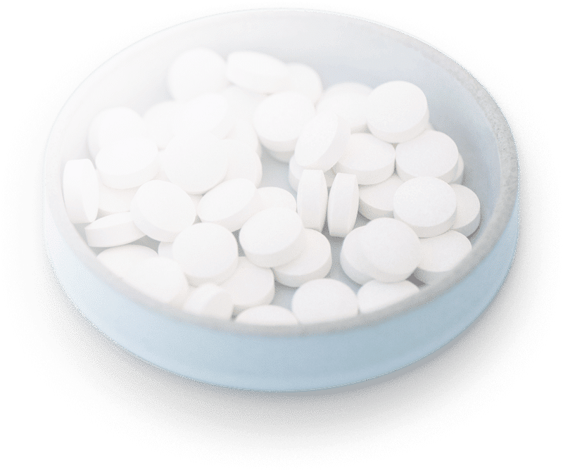 In Henley-On-Thames, a small, clear bowl filled with round, white tablets sits against a plain background, casting a gentle shadow beneath it—an emblematic scene from Healthium Clinics.