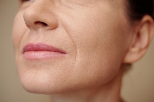 Mature,Woman,With,Nasolabial,Folds,,Selective,Focus Close-up of a womans lower face, showing her pink lips, part of her nose, and visible fine lines and wrinkles on her light skin.