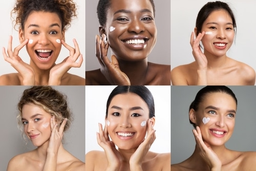 A,Collage,Image,Featuring,Six,Women,Applying,Face,Cream,To Six women with radiant skin pose smiling, applying dabs of white face cream to their cheeks. The women have different skin tones and hair types, shown in a 2x3 grid on a neutral background.