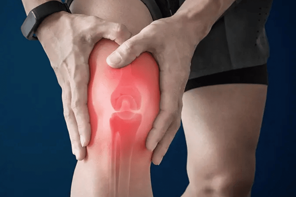 A person wearing gloves holds a test tube filled with yellow liquid, next to a laboratory centrifuge with its lid open. The centrifuge has a digital control panel and several other test tubes placed inside.