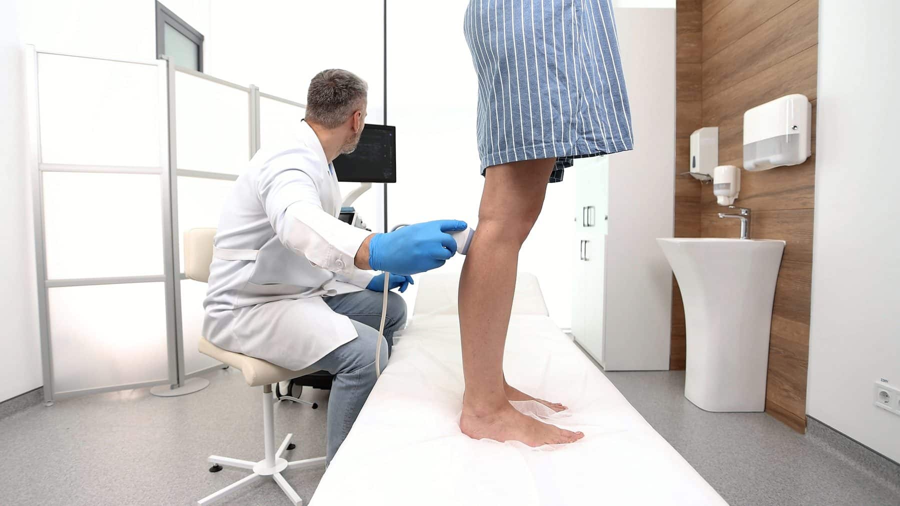 Vascular specialist examining a patient's leg veins with ultrasound at a clinic